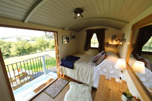 威尔斯浦Upper Gelli Luxury Holiday Lodge, Converted Dairy & Cosy Shepherds Huts的一间卧室设有一张床和一个阳台