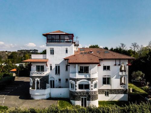 圣让-德吕兹Résidence Chateau d'Acotz - Appartements avec piscine à 600m des plages à Saint-Jean-de-Luz的一座白色的大建筑,有红色的屋顶