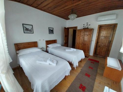 培拉特Guest House J.Prifti的配有白色墙壁和木地板的客房内的两张床