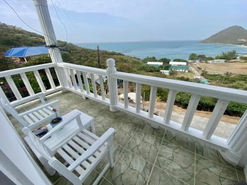 CanouanIsla Vista Apartment Canouan的阳台配有2把白色椅子,享有海景。