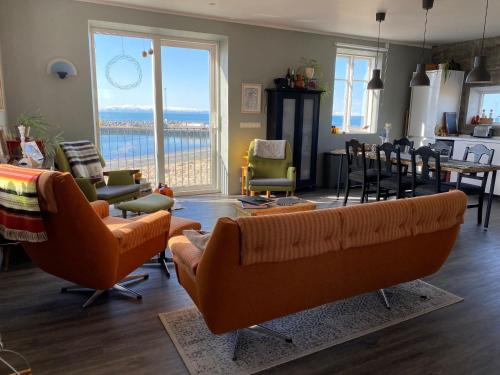 KópaskerMelar Guesthouse的客厅配有橙色沙发、桌子和椅子