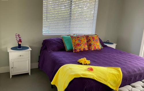 夏威夷欧申维尤The Art Garden- Hibiscus Guesthouse的一间卧室设有紫色的床和窗户