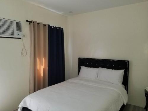 安吉利斯WYNDAM POOL VILLA的一间卧室配有一张带白色床单的床和一扇窗户。