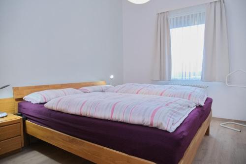 格洛米茨Haus Belvedere App 001 Stellpl 32 inkl WLAN的一间卧室配有一张带紫色床单的大床和窗户。