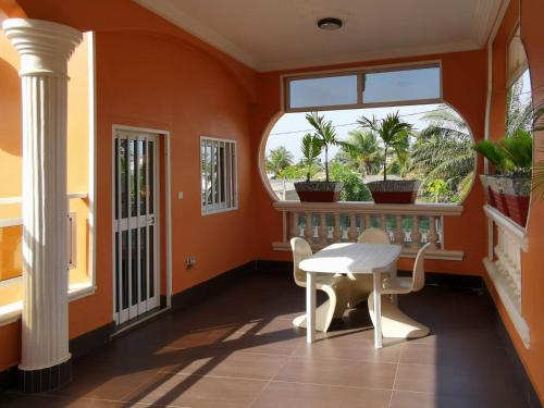 Agbata Guest House的橙色的房间,设有桌子和窗户