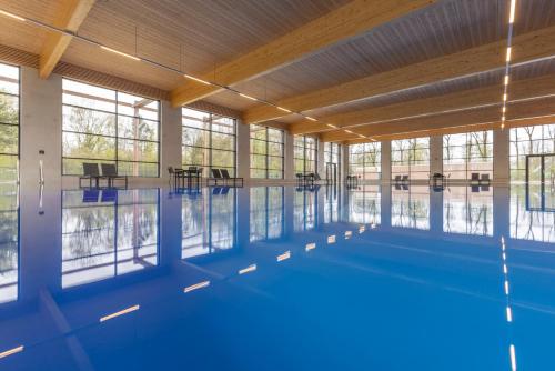 埃克斯鲁Fletcher Familiehotel De Hunzebergen的大型游泳池拥有蓝色的地板和窗户