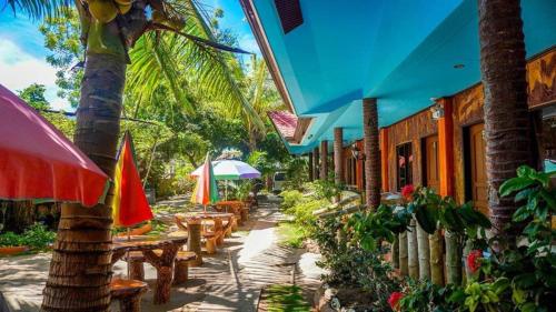 班塔延岛NorthVille Beach Resort powered by Cocotel的毗邻大楼的带桌子和遮阳伞的天井