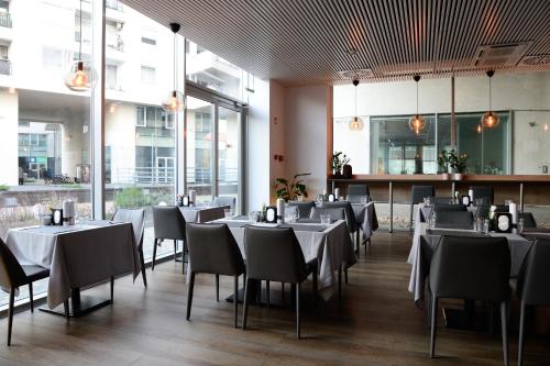 米什科尔茨Macropolis Apartments的餐厅设有白色的桌椅和窗户。