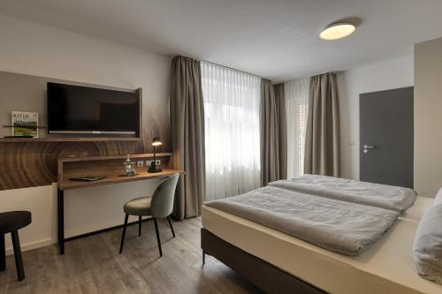 格明登Hotel Imhof的酒店客房配有一张床、一张书桌和一台电视。