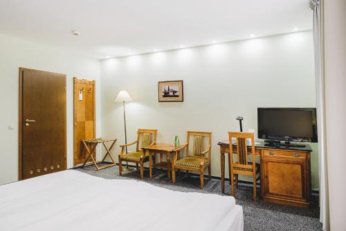 托伦索拉里斯酒店的酒店客房带一张床、一台电视、一张桌子和椅子。