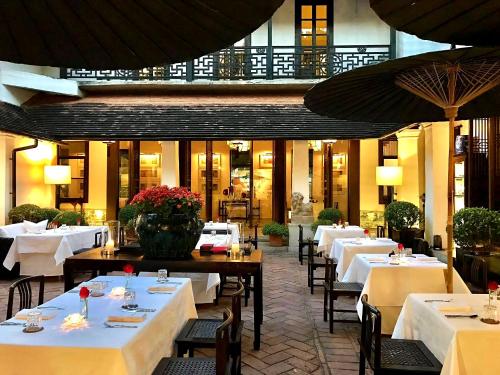 清迈Rachamankha Hotel的餐厅配有桌椅和白色的桌布