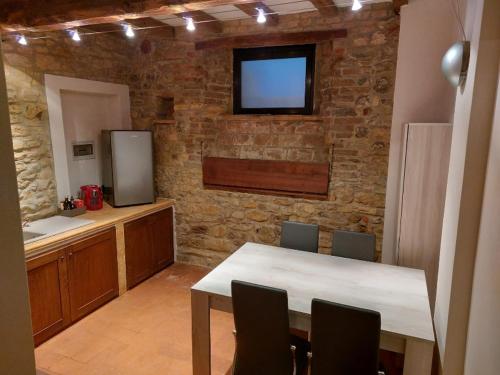 卡斯泰拉尔夸托Caolzio18的厨房配有桌子,砖墙上配有电视