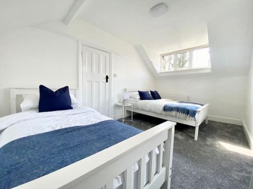 滨海绍森德Charming Seaside Cottage in Leigh-on-Sea的一间白色卧室,配有两张床和窗户
