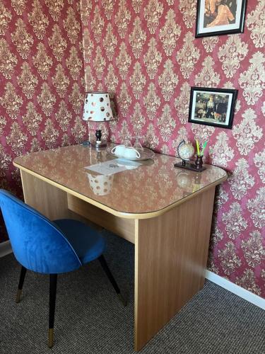 巴克乌Garsoniera Panoramic的一张带蓝色椅子的桌子,房间装饰着粉红色的壁纸