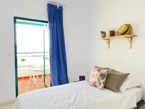 桑卢卡尔-德巴拉梅达Apartamento GUADALQUIVIR的一间卧室配有一张带蓝色窗帘的床和一扇窗户