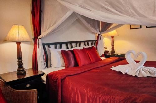 清迈提延那茹殖民饭店的一间卧室,配有红色的床,上面有心