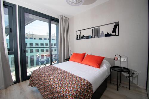 马德里Ekilibrio Hotel & Apart-Suites的一间卧室配有带橙色枕头的床和阳台