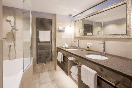 朗根费尔德丽塔酒店的浴室设有2个盥洗盆、淋浴和镜子。