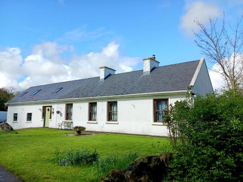 巴利霍尼斯Rural retreat near Knock的白色的房子,设有大院子和绿色草坪