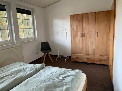 韦塞尔Landhaus am Loh的一间卧室配有一张床、一个橱柜和一把椅子
