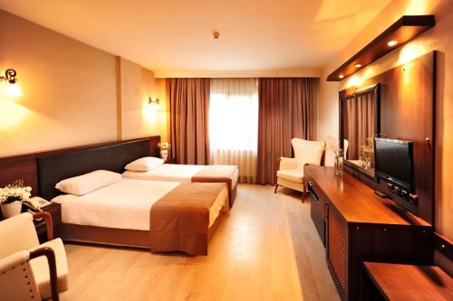伊兹密尔Üstün Hotel Alsancak的酒店客房设有两张床和一台平面电视。