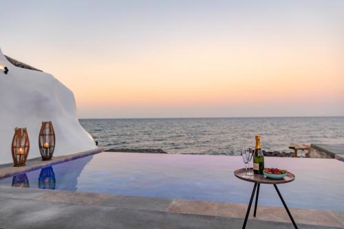 易莫洛林Casa di Mare Luxury Villas的一张桌子,旁边是海边,边喝一杯葡萄酒