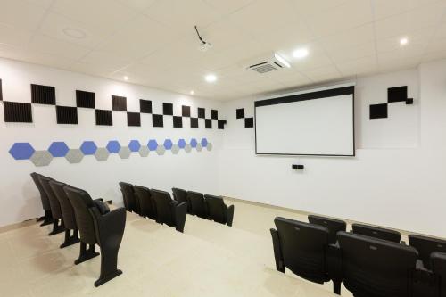 隆达Apartamentos Martalia Áticos Deluxe的一个带黑色椅子和屏幕的讲座室