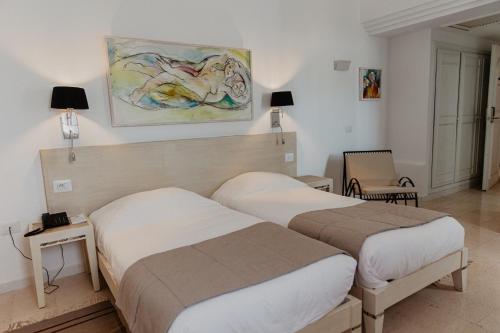 塔格梅斯Hotel Bougainvillier Djerba的酒店客房设有两张床,墙上挂有绘画作品