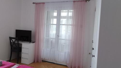 里耶卡Apolonija的卧室设有窗户和粉红色窗帘