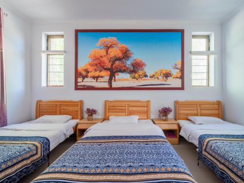 敦煌敦煌胡杨客栈的一间设有三张床的客房,墙上挂着一幅画