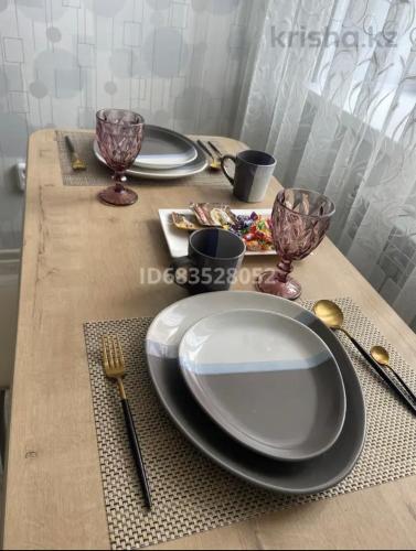 库斯塔奈Комфортабельные - уютные апартаменты в Костанай мкр Юбилейный的上面有盘子和银器的桌子