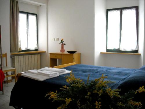圣莱奥Affittacamere Arcobaleno的一间卧室配有一张带蓝色床单的床和两个窗户。
