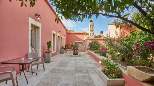 阿卡尼斯Arhontiko Arhanes Suites的粉红色房子的庭院,配有桌椅