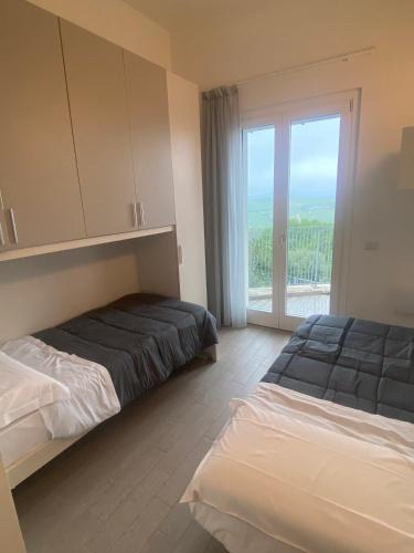 卡梅拉诺Alba - Le Grotte Rooms & Apartments的一间卧室设有两张床和大窗户