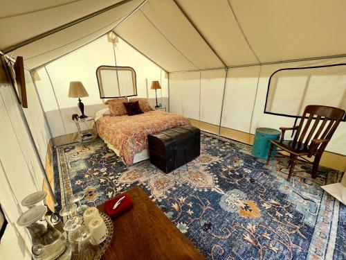 PaoniaZinnia Glamping Tent at Zenzen Gardens的帐篷内带一张床和一张桌子的房间