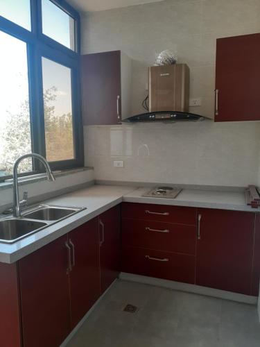 KitimēMENBi's Apartment的厨房配有棕色橱柜、水槽和窗户。