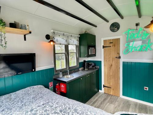 什鲁斯伯里The Orchard Retreat的一间厨房,配有绿色橱柜和一张位于客房内的床