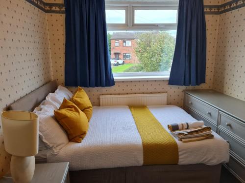 博尔顿Immaculate 3-Bed House with free parking in Bolton的小卧室配有带蓝色窗帘的床和窗户