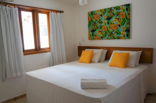塞古罗港Res Village do Bosque 03的卧室配有带橙色枕头的大型白色床