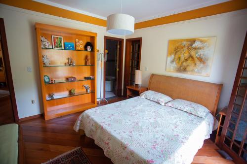 尼泰罗伊Casa a 50m da Praia de Itacoatiara Niteroi RJ的一间卧室配有床、木地板和书架
