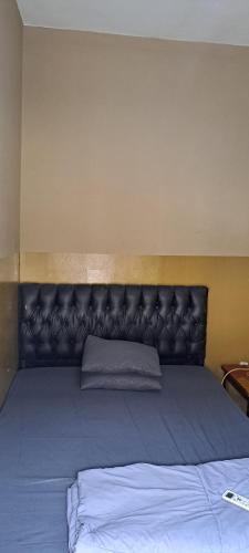 井里汶PONDOK CHILLY的一张大床,在房间里装有皮革床头板