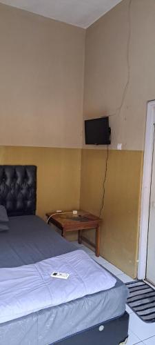 井里汶PONDOK CHILLY的卧室配有一张床,墙上配有电视。