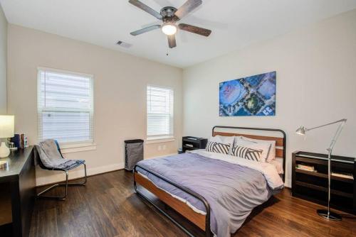 休斯顿Cozy Downtown Modern Townhome的一间卧室配有一张床、一张桌子和吊扇