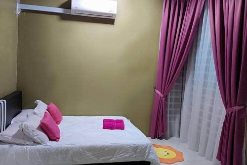 ChemorCASA Singgah Homestay的一间卧室配有带粉红色枕头的床和窗户。