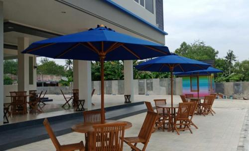 丹戎潘丹The Holiday Guest House的一组配有蓝色遮阳伞的桌椅