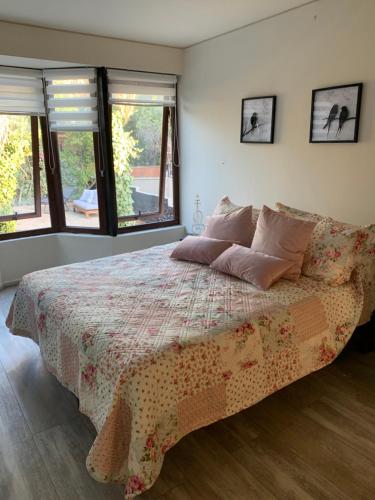 圣地亚哥Agradable casa con piscina, cerca del mall.的一间卧室配有一张带鲜花毯子和窗户的床。