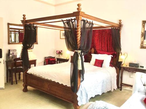 朗塞斯顿Kurrajong House的一间卧室配有带窗帘的木制天蓬床