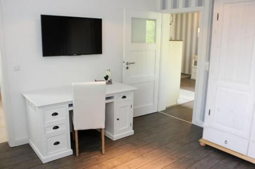 NeuhausHaus Ostseeidyll, App 01的一间设有白色书桌的客房,墙上配有电视
