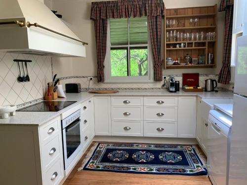 沃洛比Capers Cottage and Barn Accommodation的厨房配有白色橱柜和地板上的地毯