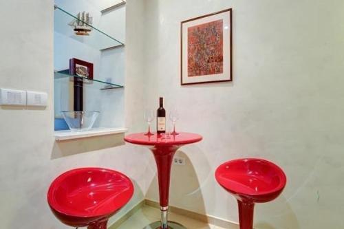 布德瓦Splendid Luxury Apartments的红桌,带两把红椅子和一瓶葡萄酒